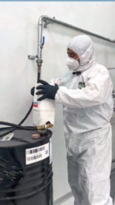 Operario con equipo sanitario llenando un tambor
